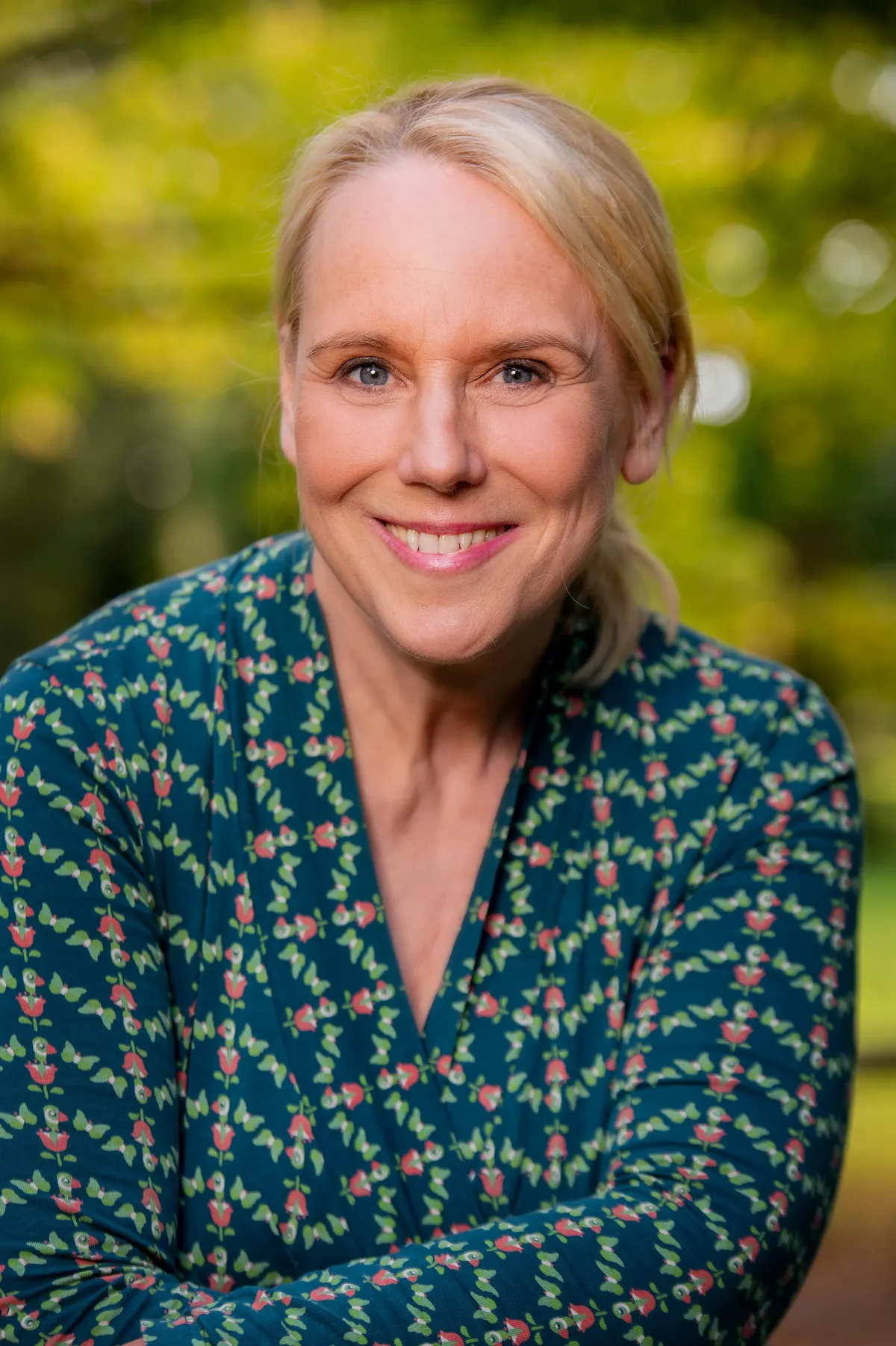 Beate Selbach, lachend vor sommerlichem Grün